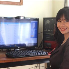 A Woman Smiling and Sitting in Front o a Computer
