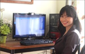 A Woman Smiling and Sitting in Front o a Computer